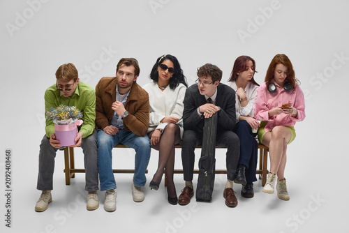 Obraz na plátně Diverse people standing in queue and interacting on white studio background