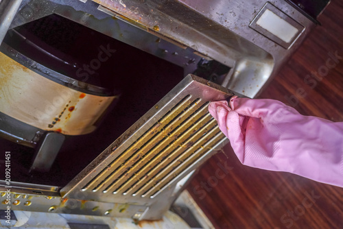 Housekeeping hands trying to removing a filters from cooker hood or chimney for cleaning. Replacing filter in modern kitchen hood or kitchen chimney maintenance for kitchen appliance.