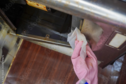 Hand in pink glove cleans kitchen hood or kitchen chimney filters. Cleaning kitchen extractor to remove grease by microfiber cloth.