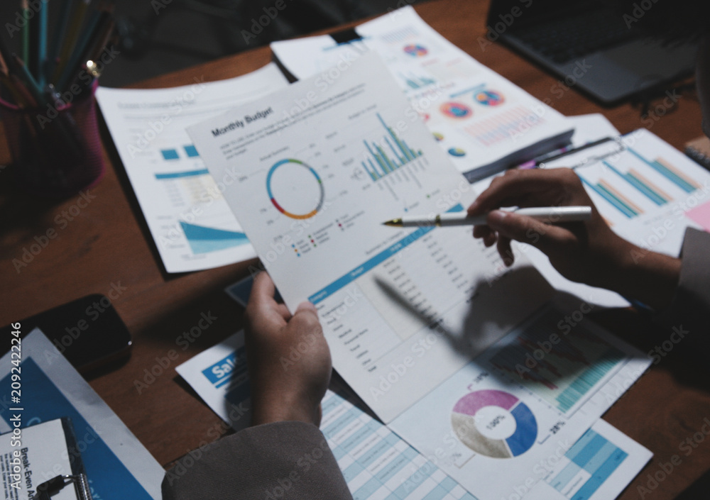 Fototapeta premium business people or accountant using calculator while working analytical business report on the workplace, accounting concept, Serious and focused financier accountant on paper work inside office,