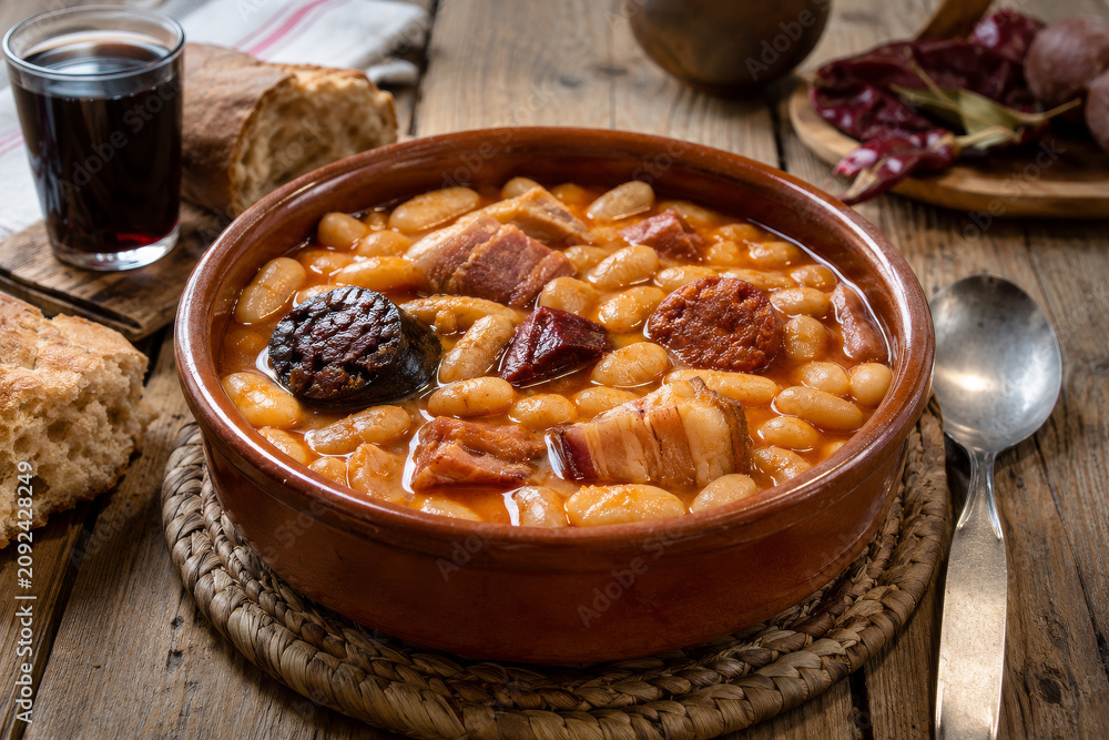 Fototapeta premium Plato de alubias con carne en una mesa de madera en un ambiente rústico y acogedor