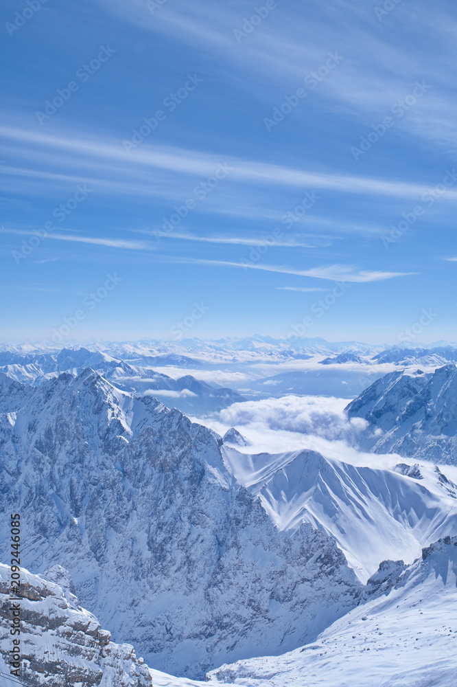 Fototapeta premium Stunning winter panoramic view of alpine mountain ranges above the clouds.