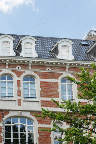 Brussels, Belgium. Historic red brick townhouse facade with dormer windows and classical architectural details in Ixelles