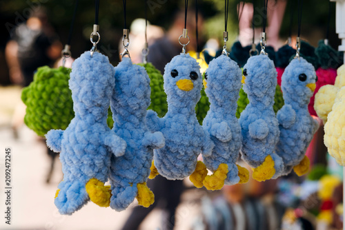 Cute handmade crochet bird keychains displayed at an outdoor artisan market.