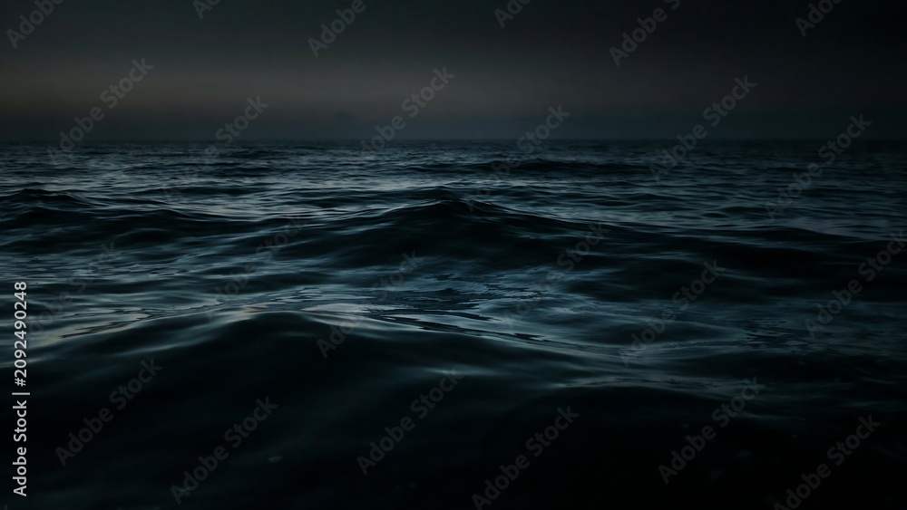 Fototapeta premium Dark and moody ocean waves gently rolling under a twilight sky at dusk