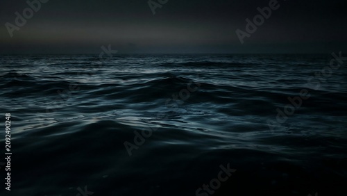 Dark and moody ocean waves gently rolling under a twilight sky at dusk