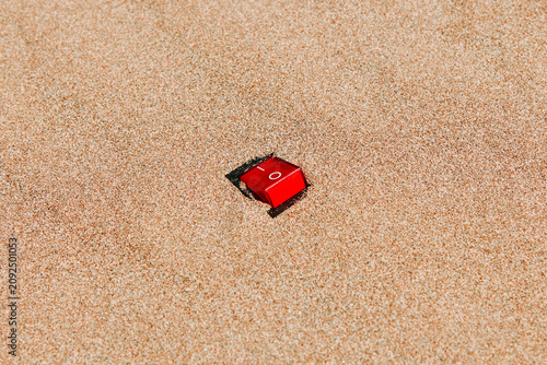 a red power switch is set to on in empty beach sand