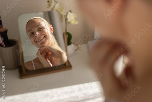 Fotografía Woman smiling happily at her reflection in a mirror, enjoying her morning beauty