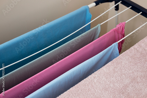 Pastel clothing hanging on indoor drying rack with soft natural light.