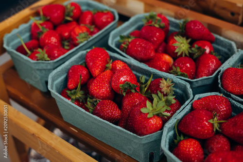 Fresh strawberries packed in recyclable paper trays at an outdoor market.