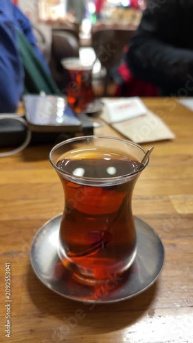 Traditional Turkish black tea is served in tulip shaped glass on wooden table inside cafe. Turkish cuisine, cafe culture, hospitality, gastronomy, travel, lifestyle, authentic dining, food culture