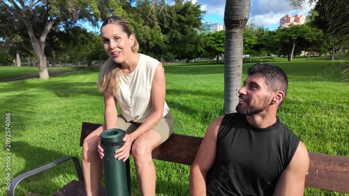 A couple chats happily on a park bench after working out