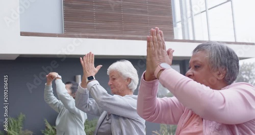 Diverse female friends following leader cue, lowering arms into prayer while centering on yoga mats