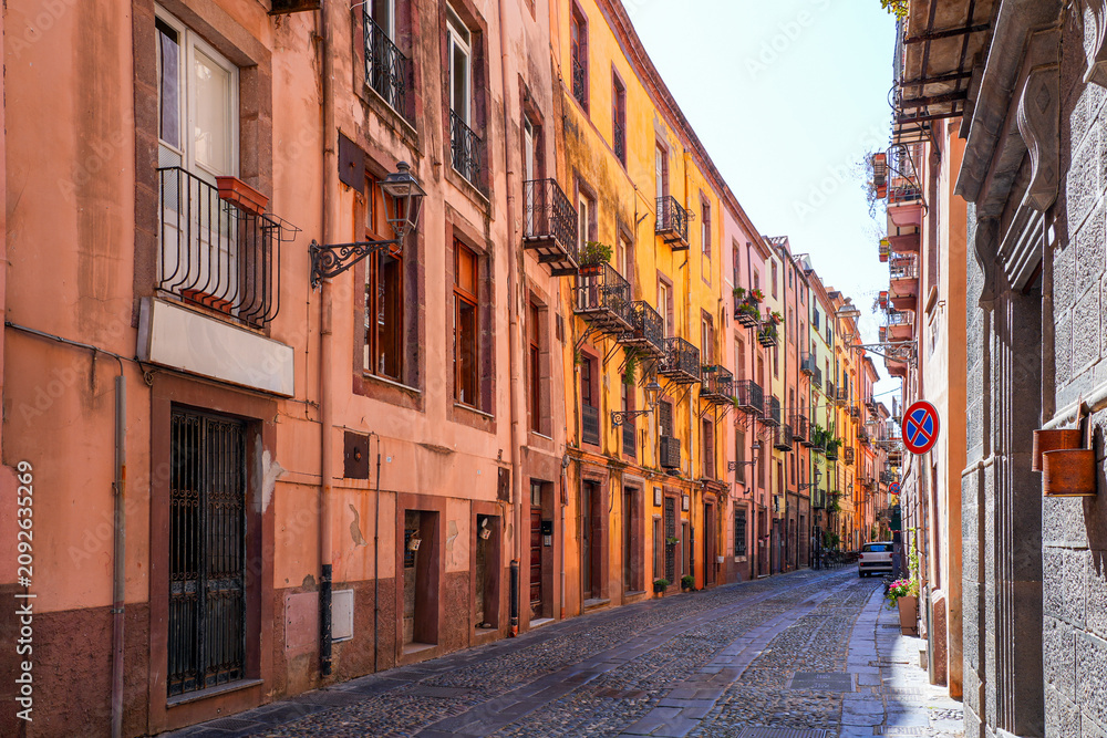 Fototapeta premium Street view of the cobbled Corso Vittorio Emanuele II in Bosa, Sardinia, Italy, with colorful historic architecture