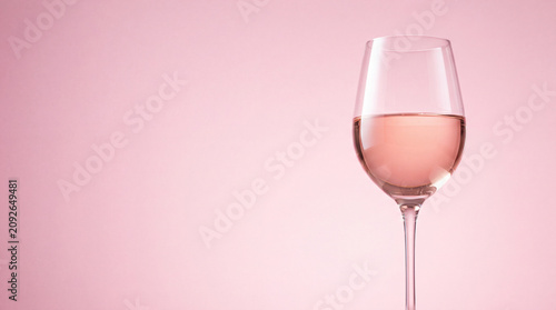 Foto Glass of rose wine against a soft pink background