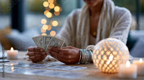 Female fortune teller reading tarot cards at a softly lit table, mystic divination practice, spiritual consultation, with copy space