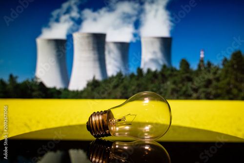 Close up of light bulb with nuclear power plant background.