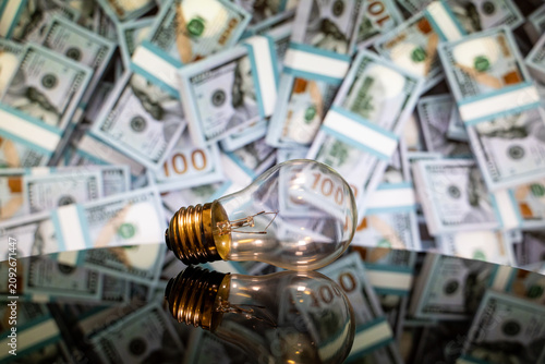 Close up of light bulb with dollar banknotes background.