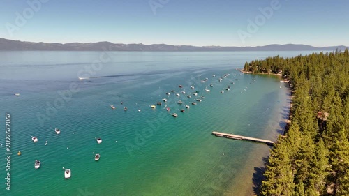 Aerial view over Lake Tahoe coastline flying forward past marina and forest