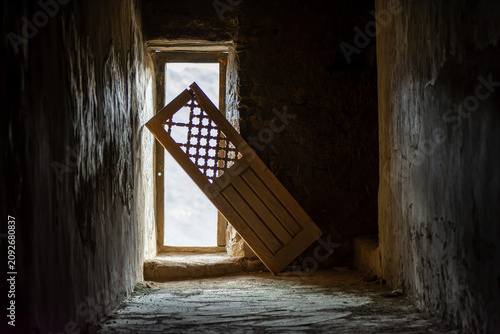 Fotografia Ancient carved wooden door in a dark corridor inside Leh Palace