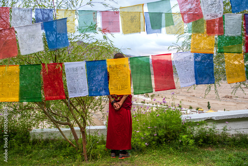 Photos Buddhist monk meditating behind colorful prayer flags