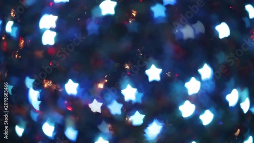 Glowing white and blue star bokeh lights on a dark night background, creating an abstract festive winter holiday atmosphere for Christmas and New Year celebration designs.