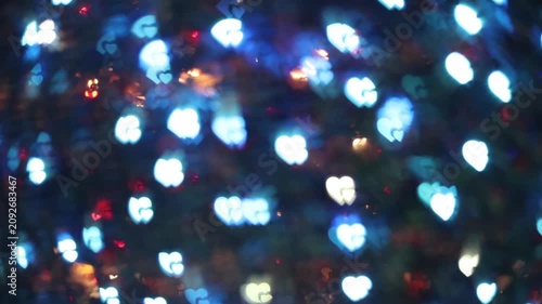 Glowing light blue white heart-shaped bokeh lights on dark night background creating magical festive romantic atmosphere for winter holiday Valentine's Day celebration.