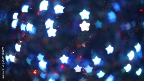 Glowing blue white star-shaped bokeh lights on dark night background festive winter magical holiday celebration abstract decoration wallpaper with copy space.