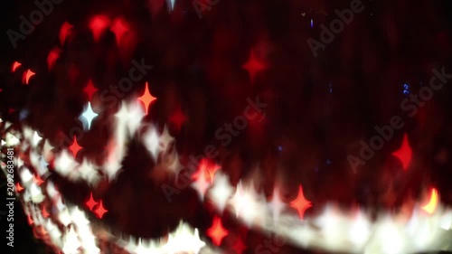 Glowing red four-pointed star bokeh lights on dark background with white diagonal light trail, festive holiday celebration and Christmas abstract sparkle decoration.