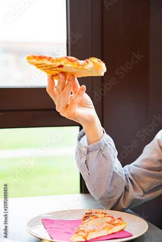 Person enjoys a pizza slice during lunch break
