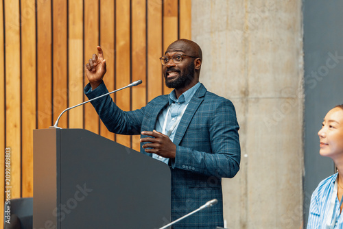 Business conference speaker giving a confident presentation at podium in modern meeting room