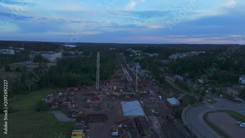 Drone footage captures railway reconstruction surrounded by forests and green fields with construction machinery under clear sky