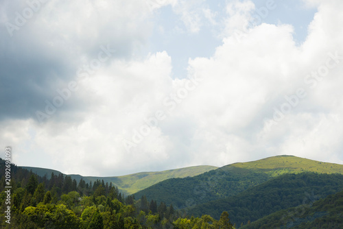 Rolling Green Mountains under Cloudy Sky with Lush Forest