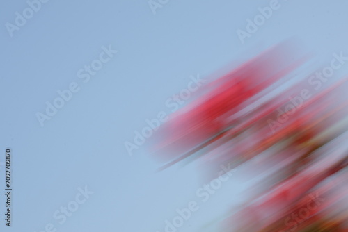 Quadro su tela Abstract motion blur background of red flowers and green leaves, intentional camera movement panning effect creating a dynamic natural texture with copy space