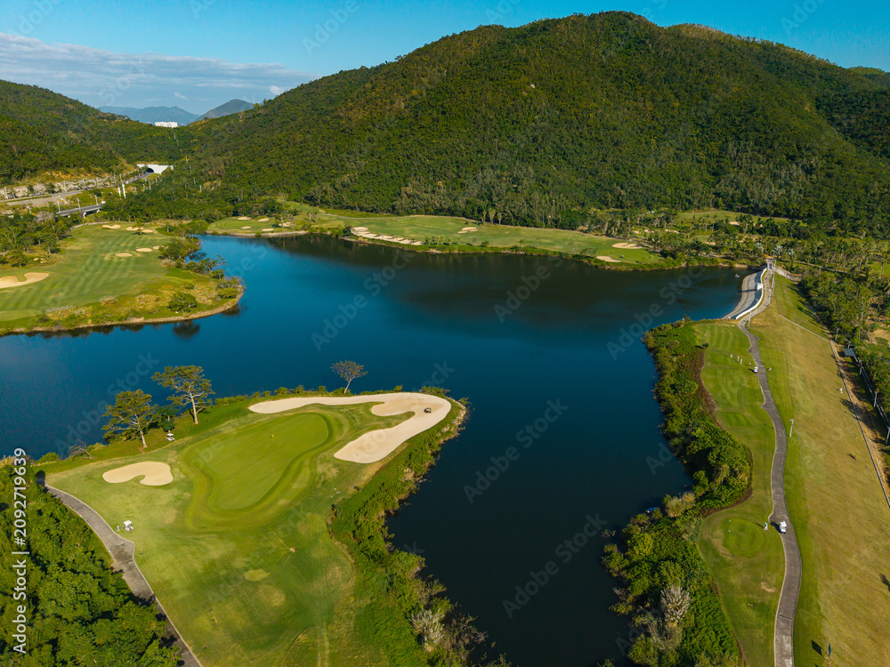 Naklejka premium Golf course island green surrounded by lake and hills aerial