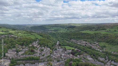 Panoramic high aerial view of the Calder valley in West Yorkshire showing the town of Hebden Bridge and the village of Mytholmroyd in summer showing the local landscape with meadows between woodland