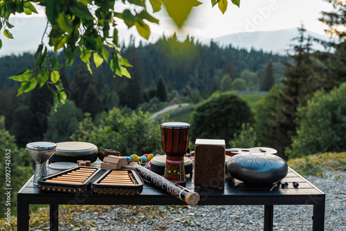 Assortment of ethnic musical instruments on a table with a scenic mountain background.