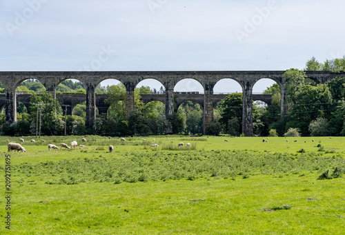 Historic viaduct with narrowboat canal boat on aqueduct arches stretching across a verdant landscape in Ceiriog valley in Chirk, Shropshire