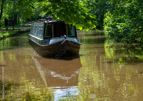 Obraz na plátně A tranquil scene featuring a narrowboat gently cruising along the scenic Llangol