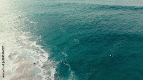 Drone aerial close view of calm Pacific Ocean surface near Pacific Beach with textured blue water and waves below