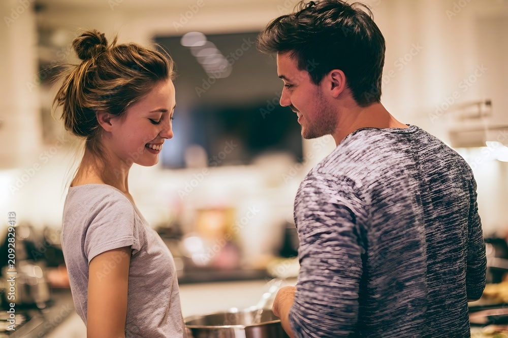 Fototapeta premium Young Couple Cooking Together in Bright Modern Kitchen