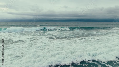 Aerial drone view of dramatic ocean waves under cloudy skies at Pacific Beach in San Diego California coastline