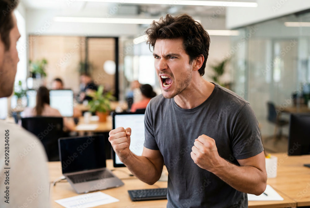 Obraz premium Furious young businessman screaming and clenching fists during office argument