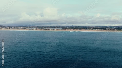 Aerial drone panorama following Pacific Beach shoreline with ocean waves and coastal landscape in San Diego California