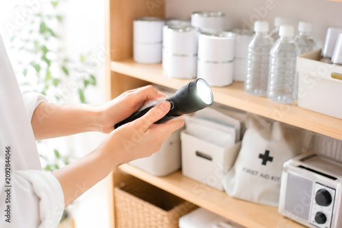 防災用品の棚から懐中電灯を取り出し確認する手元 災害への備え