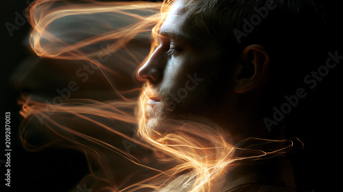 A thoughtful man surrounded by ethereal wisps of light, symbolizing introspection and creativity.