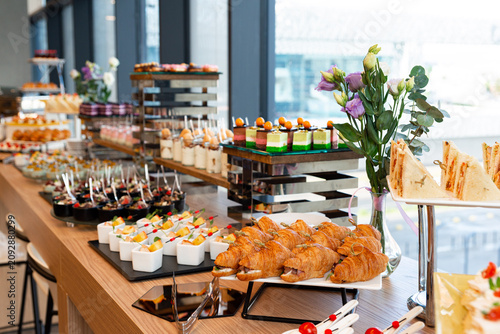 Colorful buffet display with layered mini cakes, croissants, finger foods, and desserts for event catering and party display
