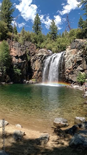 Beautiful waterfall flows into a clear pool under blue sky