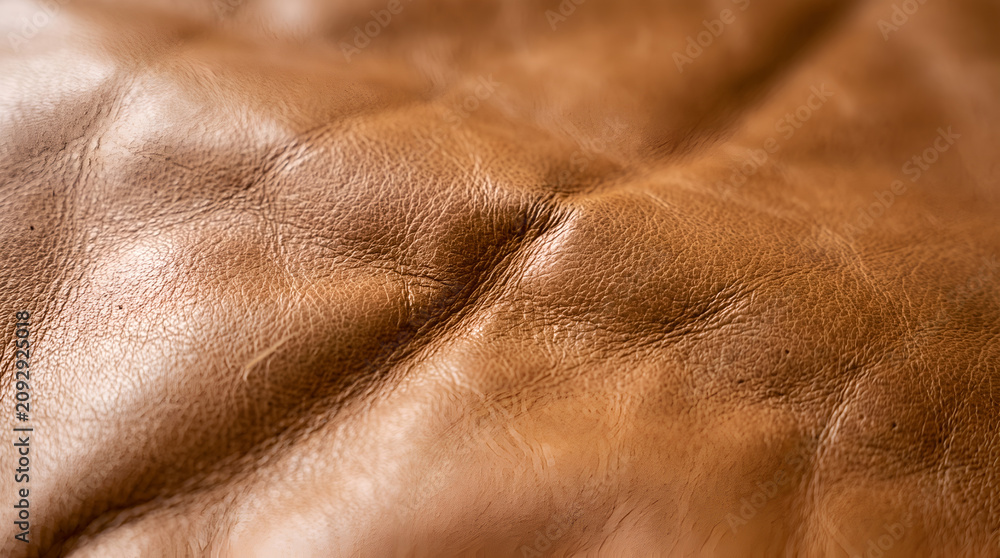 Fototapeta premium Smooth tan leather texture with soft folds natural grain and elegant brown material surface