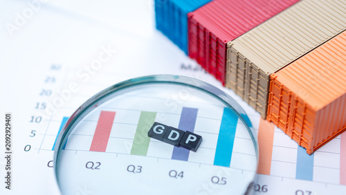 Gross domestic product growth and international trade economy concept. GDP letters on quarterly bar chart with magnifying glass and colorful shipping containers on report.
